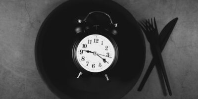 Wecker auf Teller, daneben Besteck